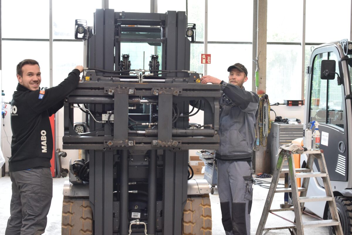 Geschäftsführer Marc Boemanns (links) und Mechaniker Heinz Schalbers schließen die Hydraulik-Kupplung an die Zinkenverstellung des Gabelstaplers an.